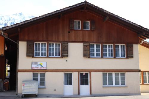 a building with a wooden roof and white doors at Royal Swiss Apartments in Ringgenberg