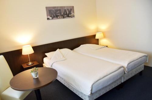 a hotel room with a bed and a table at Hotel Schuurman in Emlichheim