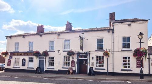 a white building on the corner of a street at The Foresters Arms in Tarporley