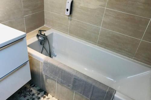 a bathroom with a bath tub with a hose at Le Cosy bohème Abbeville baie de Somme in Abbeville