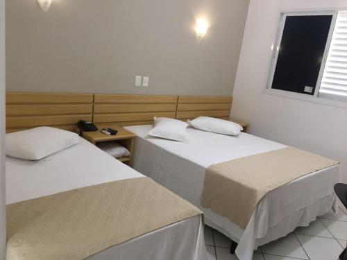a hotel room with two beds and two lamps at Hotel Sansaed in Cuiabá