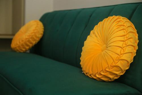 two orange pillows sitting on a green couch at Krysos Luxury Rooms in Agrigento