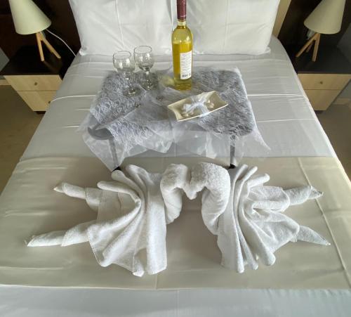 Alexander Apartments في أليكساندروبولي: سرير مع طاولة مع المناشف وزجاجة من النبيذ