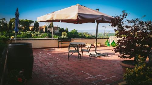 a table and chairs under an umbrella on a brick patio at Casa Anna "a lovely home in Tuscany" in Colle Val D'Elsa