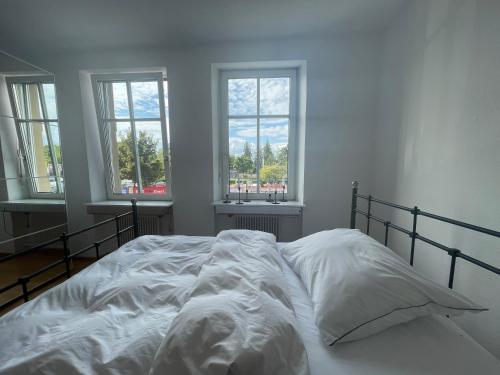 a white bed in a room with three windows at Apartments am Bodensee in Bregenz