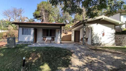 a small white house with a driveway at Chalés Vila da Serra in Serra Negra