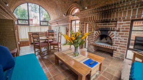 a living room with a brick fireplace and a table at Hotel San Buenaventura de Atitlán in Panajachel