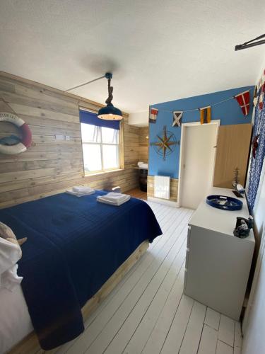 a bedroom with a blue bed and a window at The Lobster Shack in Criccieth