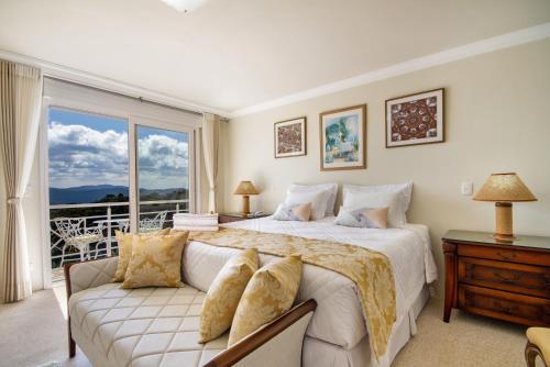 um quarto com uma cama, um sofá e uma janela em Pousada Dreams em Campos de Jordão