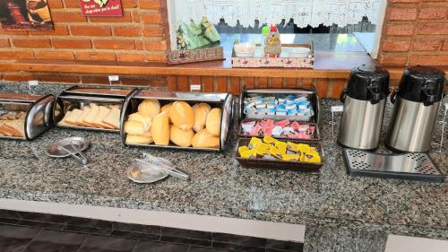 a counter with several trays of food on it at Chalés Vila da Serra in Serra Negra