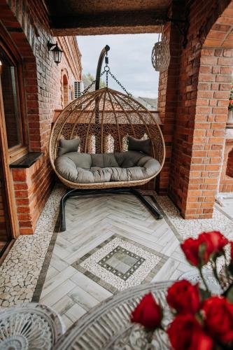 a wicker swing on a patio with red roses at Wellness Apartment, Spa i Sauna in Mieszkowice