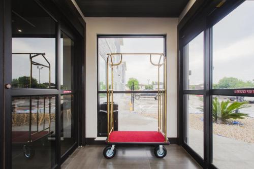 a room with a red chair in front of glass doors at Palace Inn Blue Houston East Beltway 8 in Houston