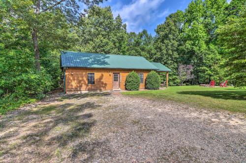 a log cabin with a green roof on a gravel driveway at Heavenly Heber Springs Hideaway Fish and Hike! in Heber Springs