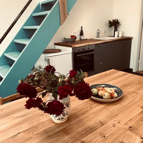 a vase with red flowers on a table with a plate of food at Rikke og Franks Svineri in Lemvig