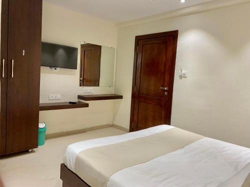a bedroom with a bed and a wooden door at Hotel Vrindavan Palace in Indore