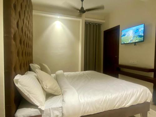 a bedroom with a bed with white sheets and pillows at Hotel Vrindavan Palace in Indore