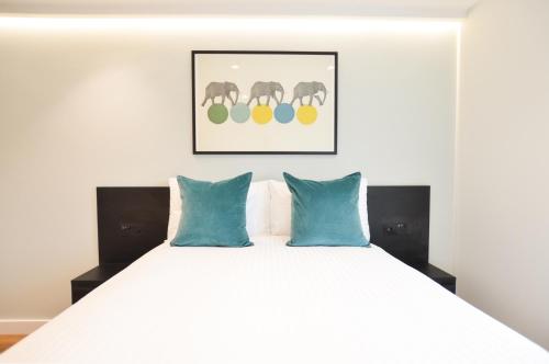 a bedroom with a large white bed with blue pillows at Earls Court West Serviced Apartments by Concept Apartments in London