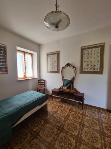 een slaapkamer met een bed, een spiegel en een stoel bij Appartmento Rustico Montagna Val Maira Castellaro in Macra