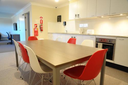 a kitchen with a wooden table and red chairs at Comfort Inn Serenity Bathurst in Bathurst