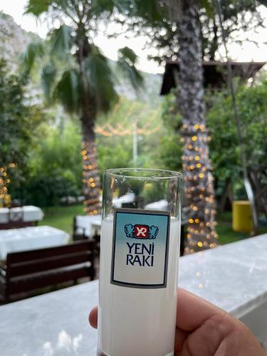 a person holding a glass of milk in front of a table at Kibala Hotel in Cıralı