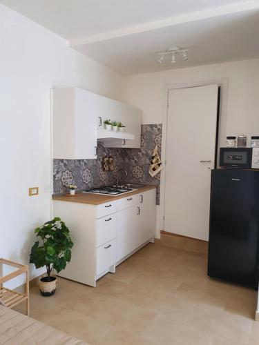 La cuisine est équipée de placards blancs et d'un réfrigérateur noir. dans l'établissement Loft Ionios, à Noto Marina