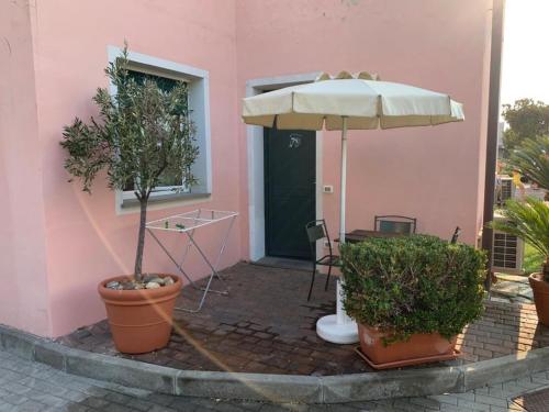 a pink building with a table and an umbrella at Residence Borgomare in Albenga