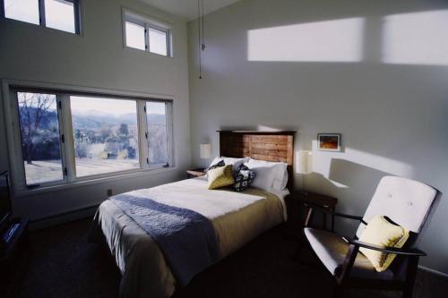 a bedroom with a bed and a chair and a window at Charming, Spacious, Contemporary Mountain Retreat in Whitehall
