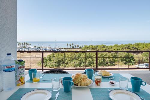 a table with plates of food and a view of the beach at Ocean View Balcony Carcavelos Beach 2-min Walk, AC in Carcavelos