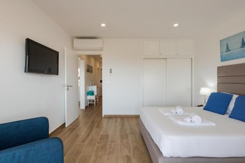 a bedroom with a white bed and a blue couch at Ocean View Balcony Carcavelos Beach 2-min Walk, AC in Carcavelos