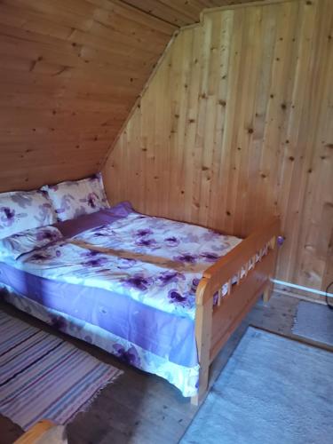 a bedroom with a bed in a wooden room at Fontana erdélyi vendégház in Odorheiu Secuiesc