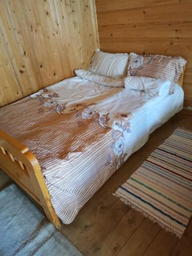 a bed in a room with a wooden wall at Fontana erdélyi vendégház in Odorheiu Secuiesc
