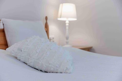 a white pillow on a white bed with a lamp at die weisse Wand in Weissensee