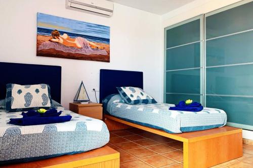 2 camas individuales en una habitación con una pintura en la pared en Villa Papagayo Relax, en Playa Blanca