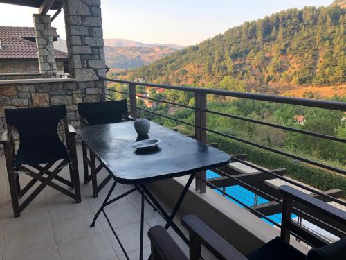 una mesa y sillas en un balcón con vistas en Luxurious Maisonette in the countryside with a pool en Kalavrita