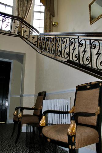 two chairs in a room with a stair railing at The Station Hotel and Banqueting in Dudley