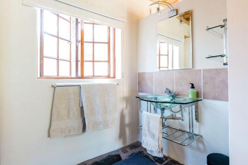 a bathroom with a sink and a mirror and towels at Onbedacht Cottage in Graaff-Reinet
