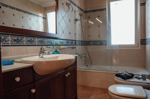a bathroom with a sink and a toilet and a mirror at Menurka - Port d'Addaia in Port d'Addaia