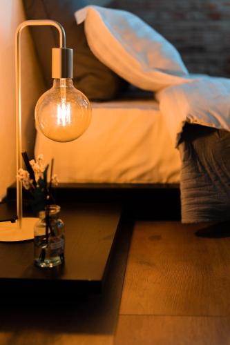 a lamp sitting on a table next to a bed at Craita Merelor The PLACE in Aninoşani