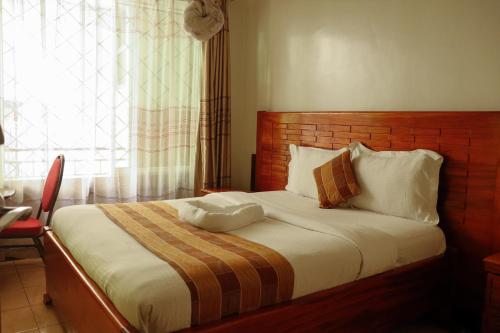 a bedroom with a bed with a wooden headboard and a window at Hotel Sunrise in Nairobi