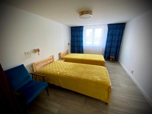 a bedroom with two beds and a blue chair at Rynek_28 in Ciężkowice