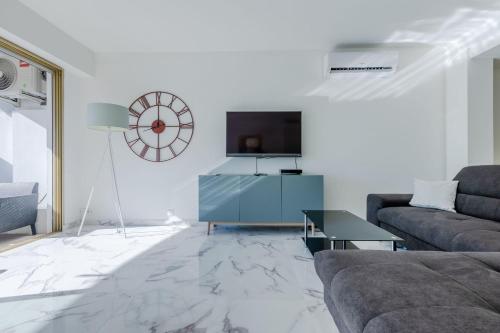a living room with a couch and a clock on the wall at Right by the beaches 90m2 on the Croisette in Cannes