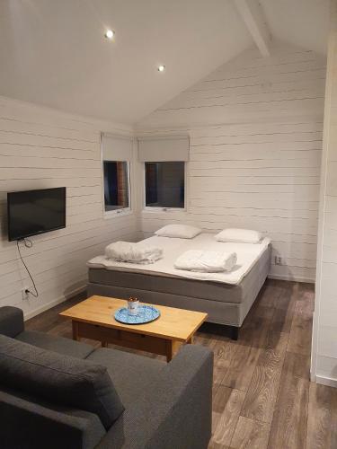 a bedroom with a bed and a couch and a table at Skogsbäckens stugby AB in Tomelilla