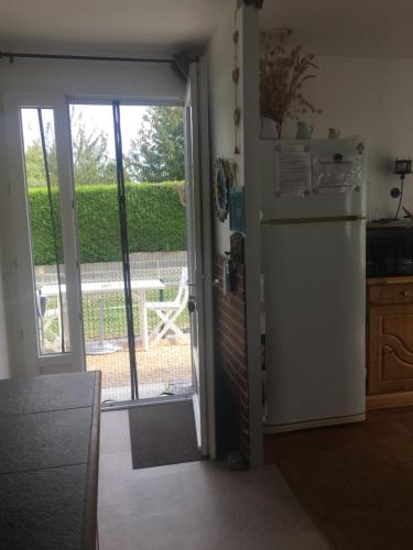 a kitchen with a refrigerator and a door to a yard at JARDIN DE CAMPAGNE in Ully-Saint-Georges