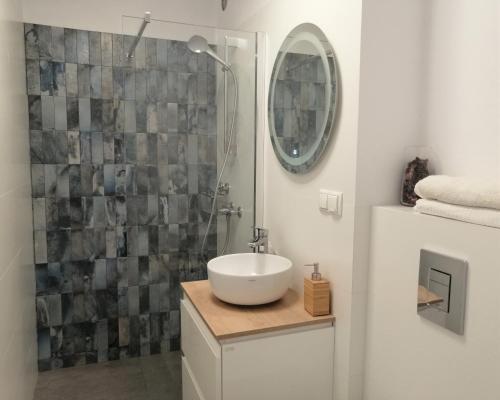 a bathroom with a sink and a shower with a mirror at Meva Apartment Gdańsk in Gdańsk