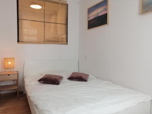 a white bed with two brown pillows on it at Meva Apartment Gdańsk in Gdańsk