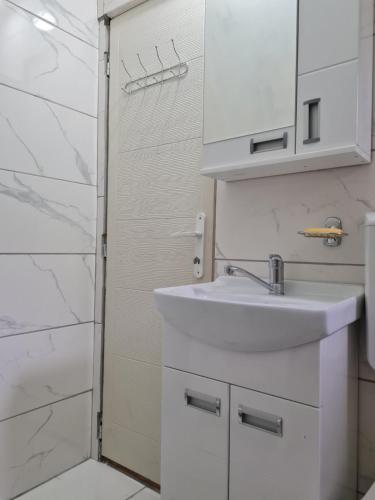 a white bathroom with a sink and a shower at Apartmani Radaković in Vrdnik
