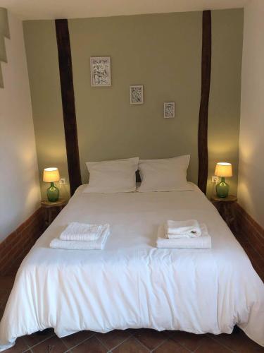 a bedroom with a white bed with two towels on it at L'ancienne Forge in Allemant
