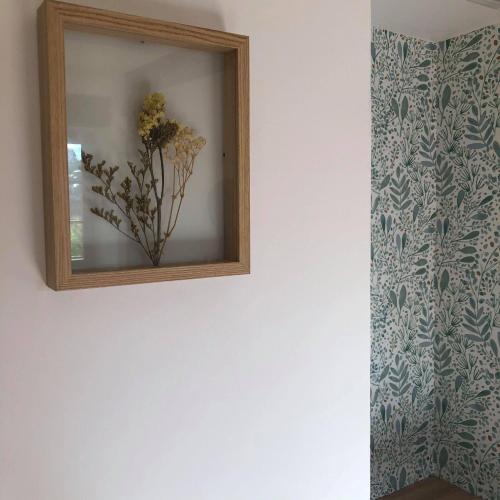 un miroir sur un mur avec un vase de fleurs dans l'établissement L'ancienne Forge, à Allemant