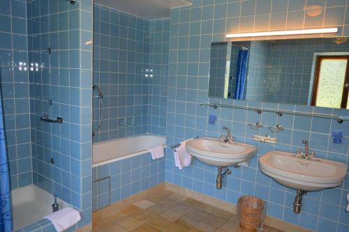 a blue tiled bathroom with two sinks and a tub at Hotel Garni Sonnenhof in Rottach-Egern