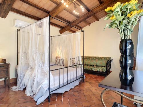 a room with a bed with curtains and a vase of flowers at Agriturismo Dominus Domenico in Cortona